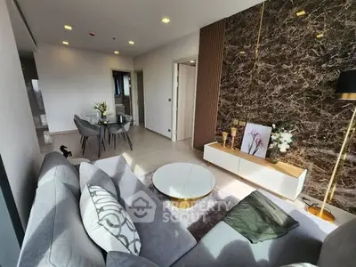 Modern living room with elegant decor and dining area, featuring marble accent wall and stylish furniture.