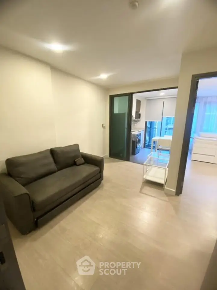 Modern apartment interior with cozy living room and open kitchen layout, featuring sleek furniture and bright lighting.