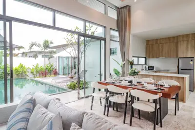 Luxurious open-plan living room with pool view and modern kitchen in tropical villa.