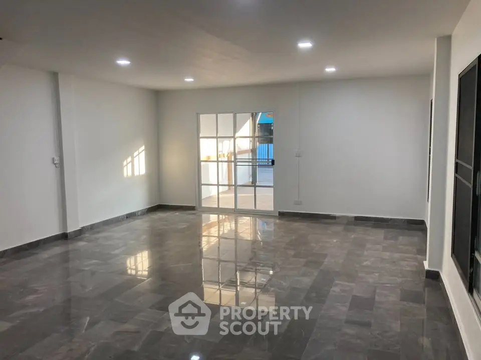 Spacious modern living room with glossy tiled flooring and ample natural light.