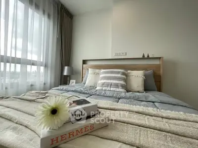 Cozy bedroom with stylish decor and large window offering natural light.