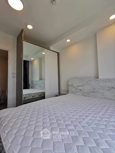 Modern bedroom with large mirror and elegant marble headboard in a stylish apartment.