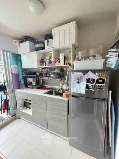Modern kitchen with sleek cabinets, stainless steel fridge, and open shelving for efficient storage.