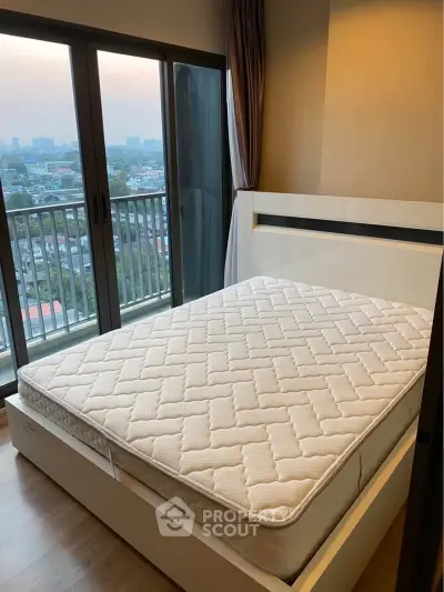 Modern bedroom with large window and city view, featuring a comfortable bed and stylish decor.