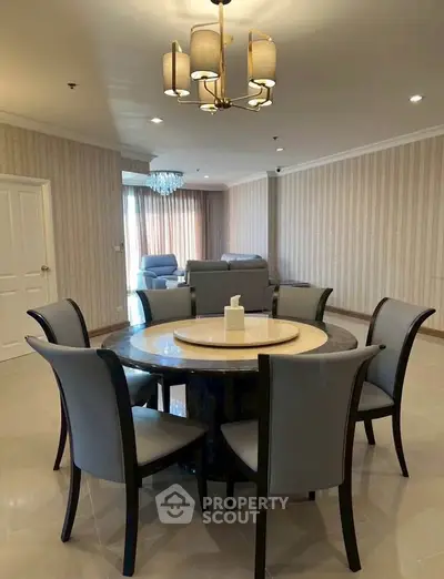 Spacious dining area with elegant round table and modern chandelier in a stylish living room.