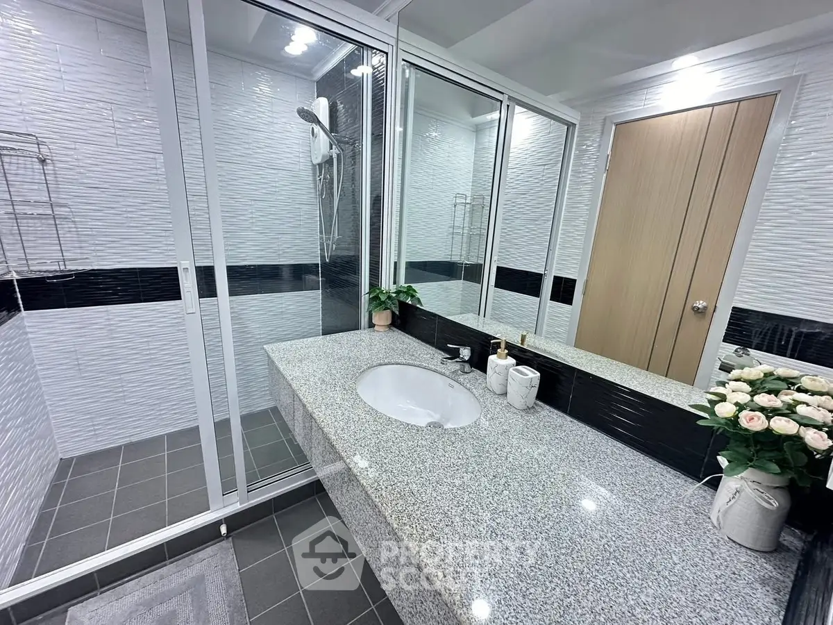Modern bathroom with sleek design, featuring a granite countertop and glass shower enclosure.