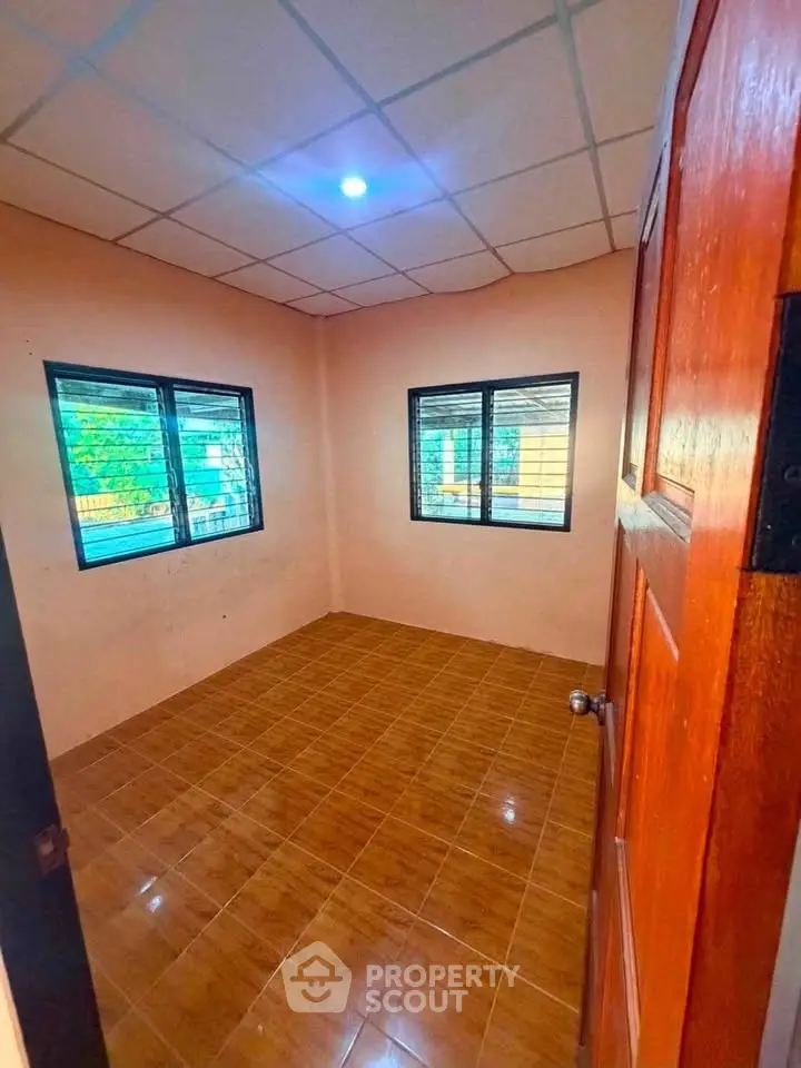 Cozy empty room with tiled floor and large windows, perfect for customization.