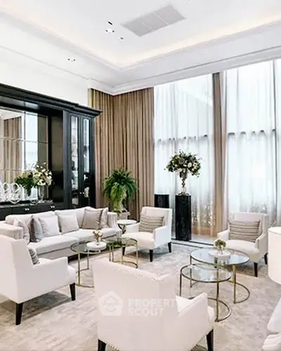 Luxurious living room with elegant decor and high ceilings, featuring plush seating and stylish glass tables.