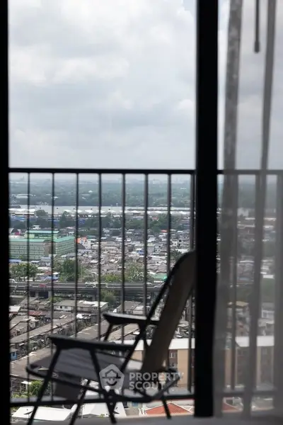 Stunning cityscape view from a high-rise balcony with a cozy chair.