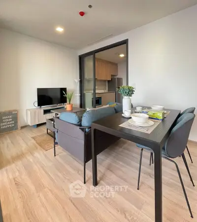 Modern living room with open kitchen, stylish furniture, and cozy dining area in a contemporary apartment.