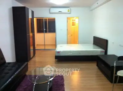 Modern studio apartment with sleek furniture and wooden flooring, featuring a cozy bed and stylish decor.