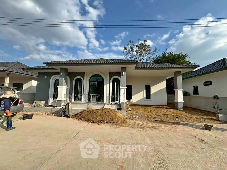 Modern single-story house with elegant arches and spacious driveway under a clear blue sky.