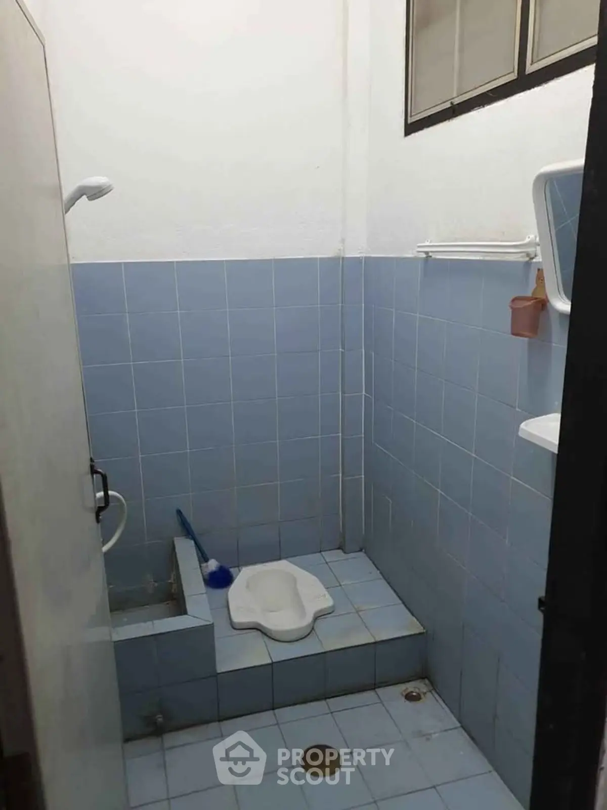 Compact bathroom with blue tiles and squat toilet, ideal for minimalist design.