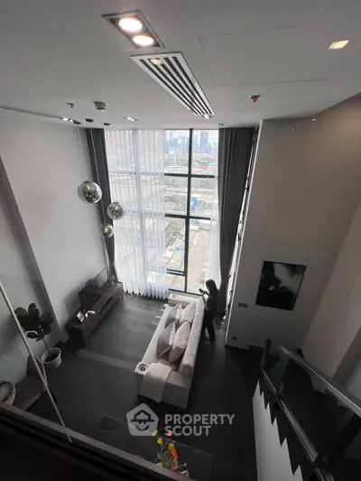 Stunning high-ceiling living room with floor-to-ceiling windows and modern decor.