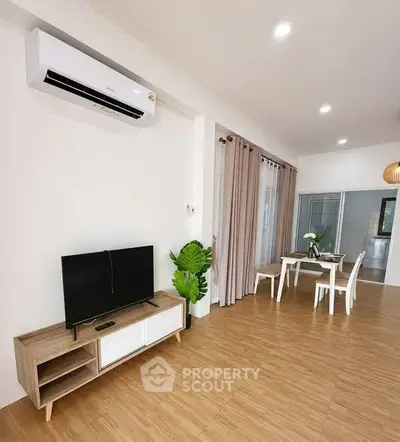 Modern living room with air conditioning and dining area, featuring wooden flooring and elegant decor.