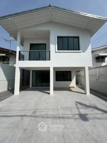 Modern two-story house with spacious driveway and sleek balcony design.