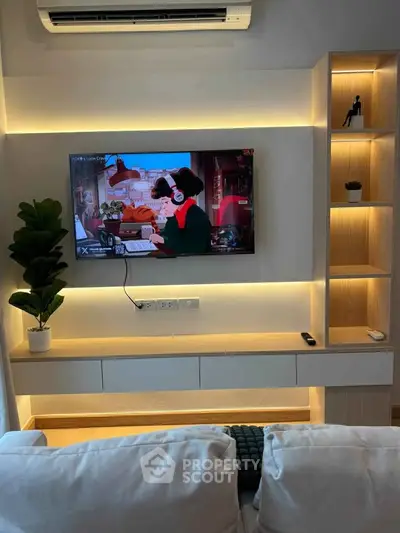 Modern living room with stylish TV setup and ambient lighting, featuring sleek shelving and cozy seating.
