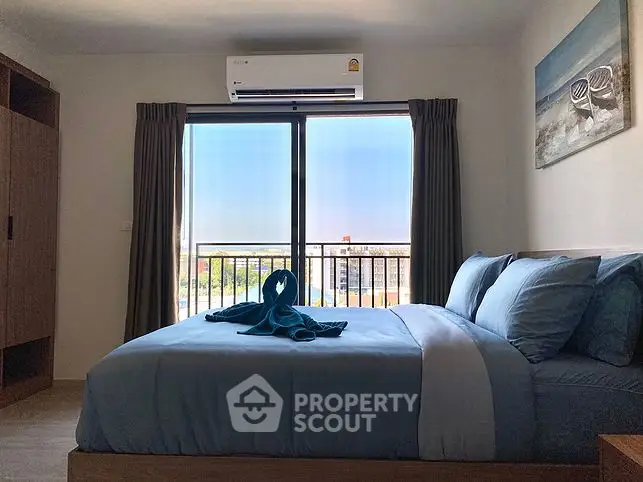 Cozy bedroom with modern decor, featuring a comfortable bed and a scenic balcony view.