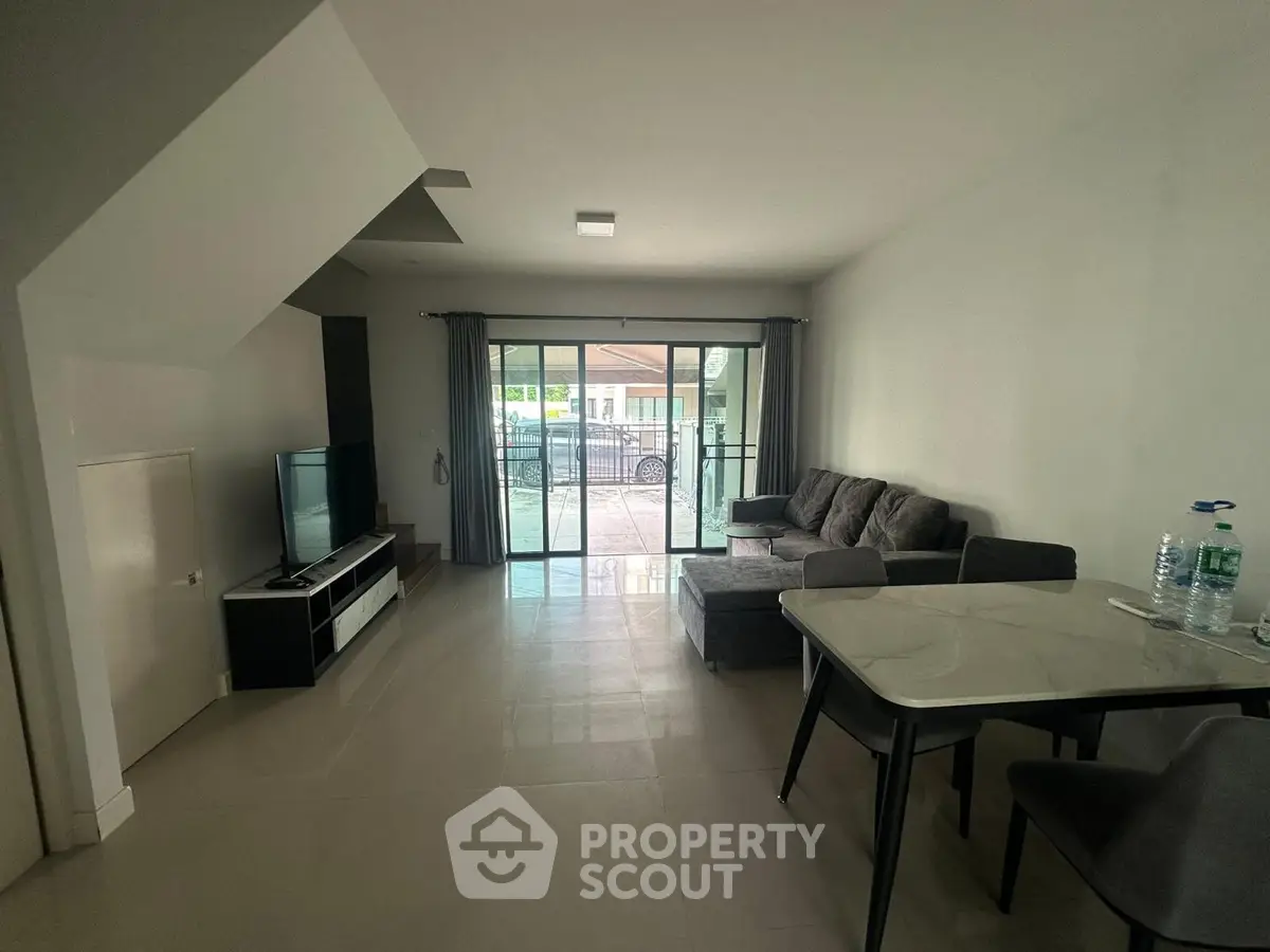Spacious living room with modern furniture and large windows opening to a patio, perfect for relaxation.