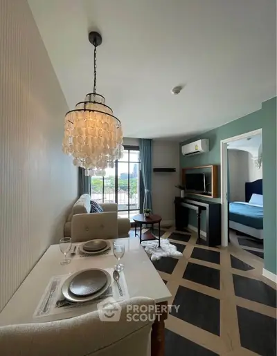 Chic modern living room with elegant chandelier and open layout leading to a cozy bedroom.