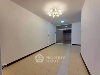 Spacious empty room with modern lighting and tiled flooring, ideal for customization.