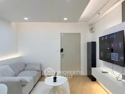 Modern living room with sleek design, featuring a cozy sofa, wall-mounted TV, and minimalist decor.