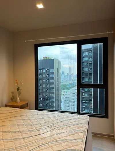 Modern bedroom with city view from large window in high-rise apartment