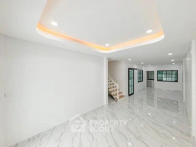 Spacious modern living room with elegant marble flooring and recessed lighting.