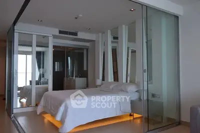 Modern bedroom with glass walls and ambient lighting in luxury apartment.