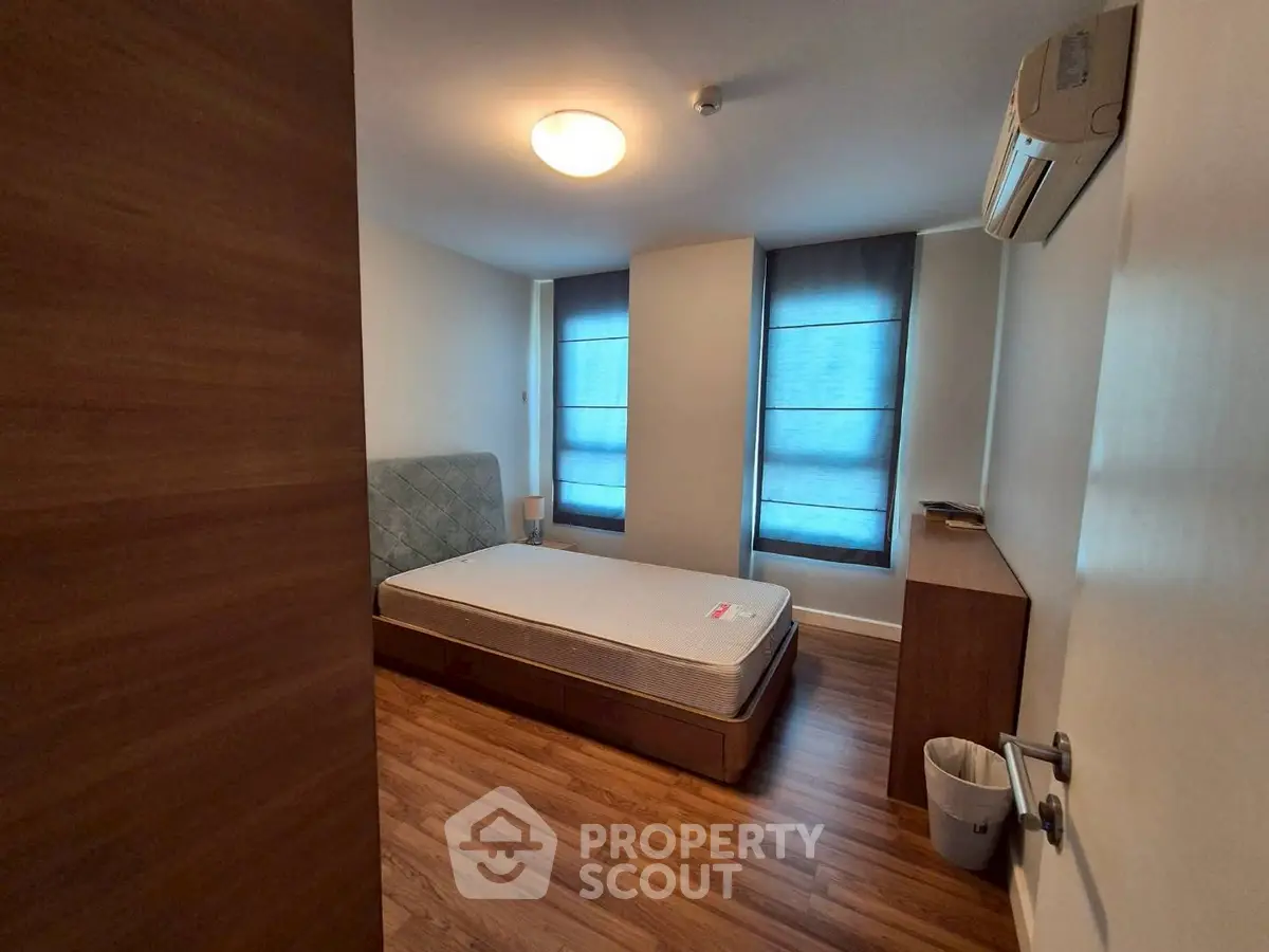 Cozy bedroom with wooden flooring and modern air conditioning unit.