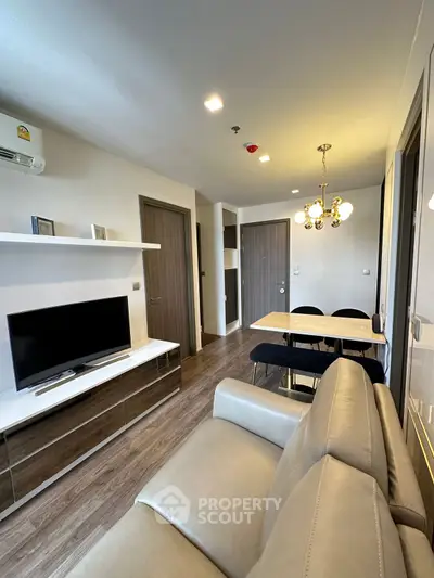 Modern living room with sleek furniture and dining area in open layout apartment.