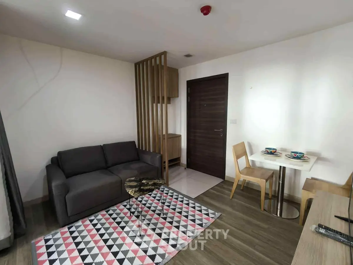 Modern living room with stylish furniture and geometric rug in a cozy apartment setting.