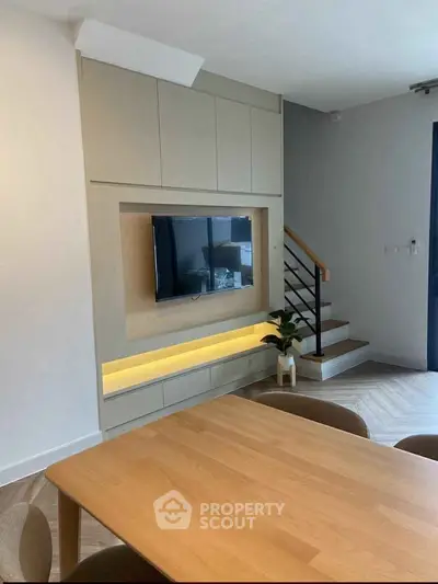 Modern living room with sleek TV setup and stylish staircase