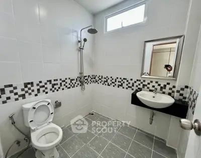 Modern bathroom with sleek design, featuring a shower, toilet, and stylish sink in a tiled setting.