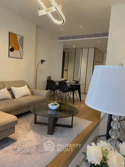 Modern living room with stylish decor and open dining area, featuring elegant lighting and contemporary furniture.