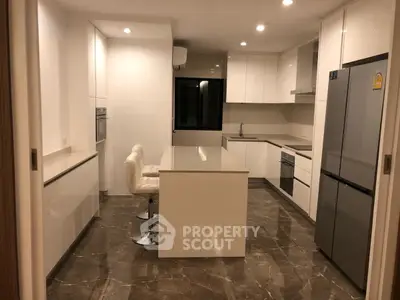 Modern kitchen with sleek white cabinetry and marble flooring, featuring a central island and stainless steel appliances.