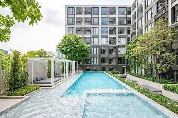 Modern apartment complex with luxurious outdoor pool and lush greenery.