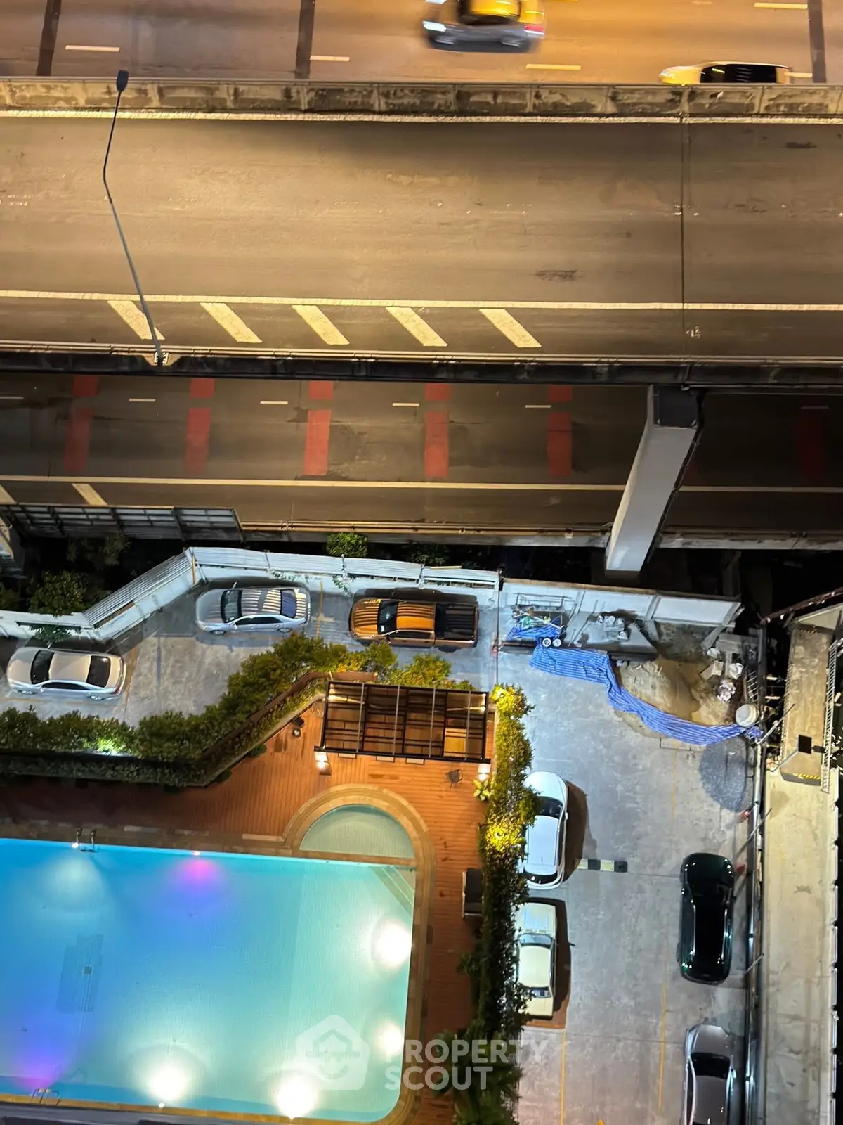 Stunning aerial view of a modern apartment complex with a pool and parking area, perfect for urban living.