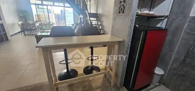 Modern open-plan living area with stylish bar seating and compact fridge, perfect for entertaining.