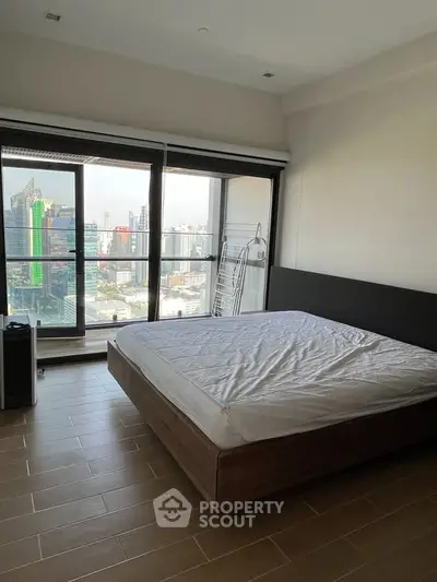 Spacious bedroom with stunning city view and modern furnishings in high-rise apartment.
