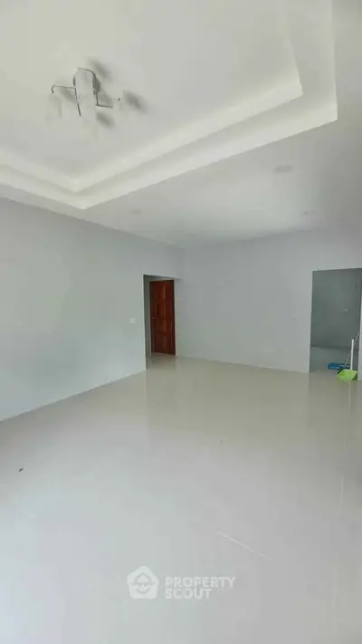 Spacious unfurnished room with white tiled flooring and modern ceiling design, ideal for customization.