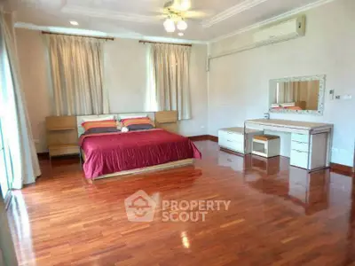 Spacious bedroom with polished wood floors and elegant furnishings