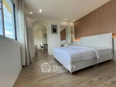 Spacious modern bedroom with elegant decor and large windows offering natural light.