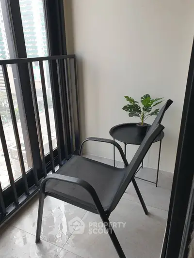 Cozy balcony with modern chair and small table, perfect for relaxation and enjoying city views.