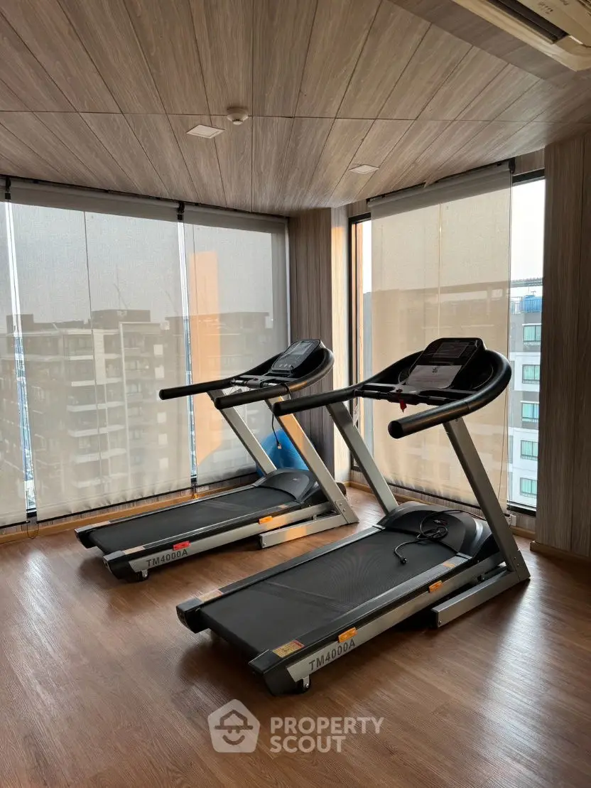 Modern gym with treadmills and city view in luxury apartment building.