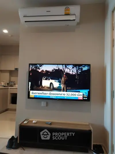 Modern living room with wall-mounted TV and air conditioning in a cozy apartment.