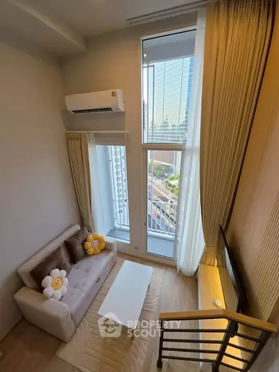 Modern loft living room with high ceilings and city view, featuring cozy sofa and stylish decor.