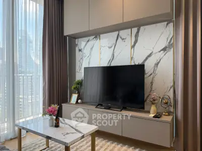 Modern living room with marble accents and large TV, featuring elegant decor and natural light.
