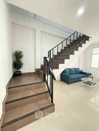 Modern interior with sleek staircase and cozy seating area in a bright living space.