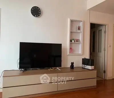 Modern living room with sleek TV stand and wall clock, showcasing minimalist design and cozy ambiance.